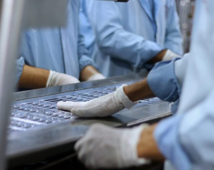 Workers in a pharmaceutical facility packaging tablets in Islamabad.